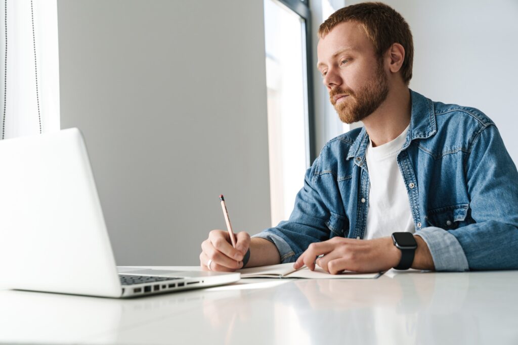 Photo of man writing down the pros and cons of renting a coworking space nearby