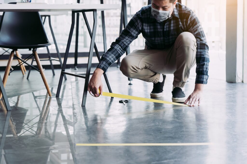 male workers preparing masking tape to symbolize social distancing